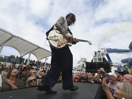 3 | Monsters Of Rock Cruise Guitarist performing on an outdoor stage as a cheering crowd watches from the front rail.